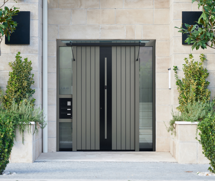 Porte d’entrée gris-noir avec partie latérale vitrée, auvent et boîte aux lettres