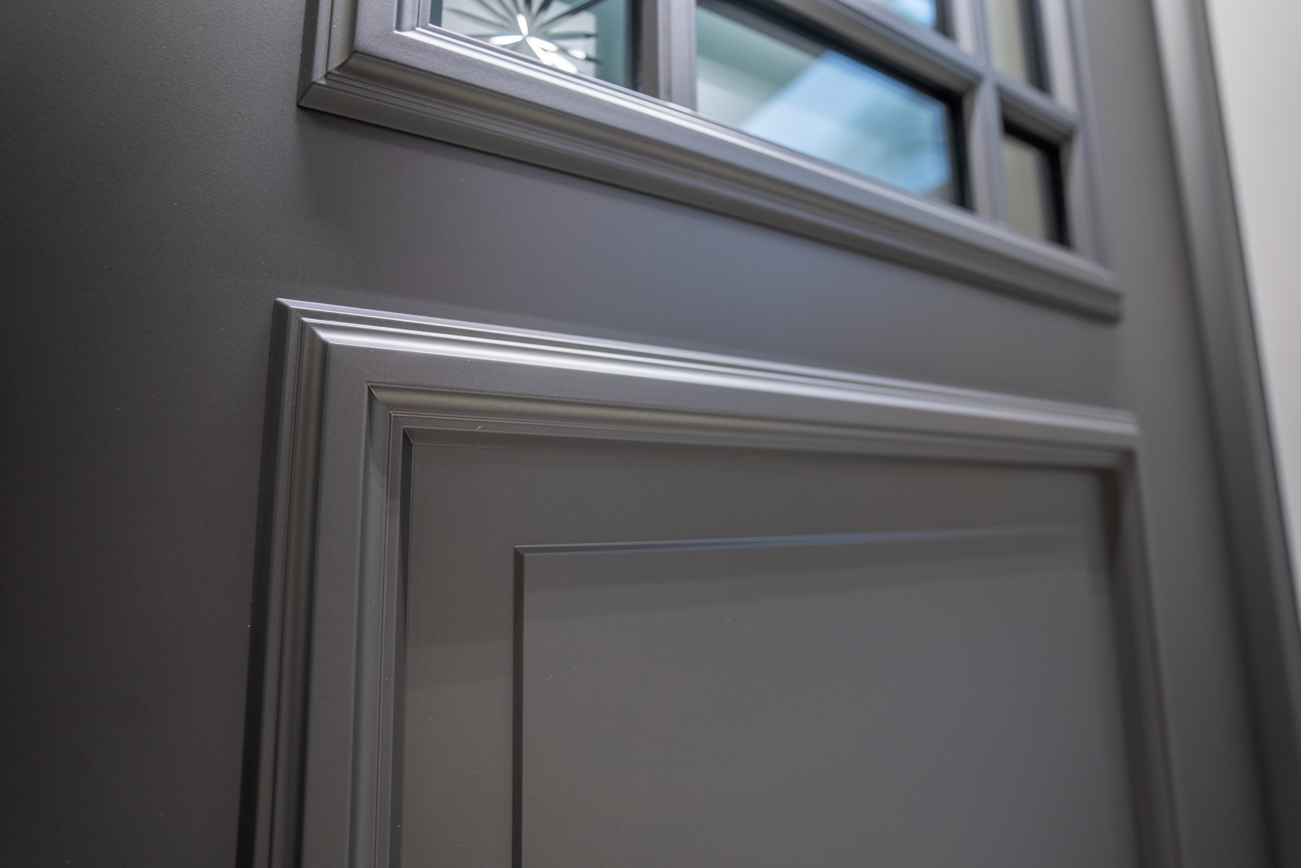 Détail décoratif avec encadrements soulignés sur une porte d’entrée grise